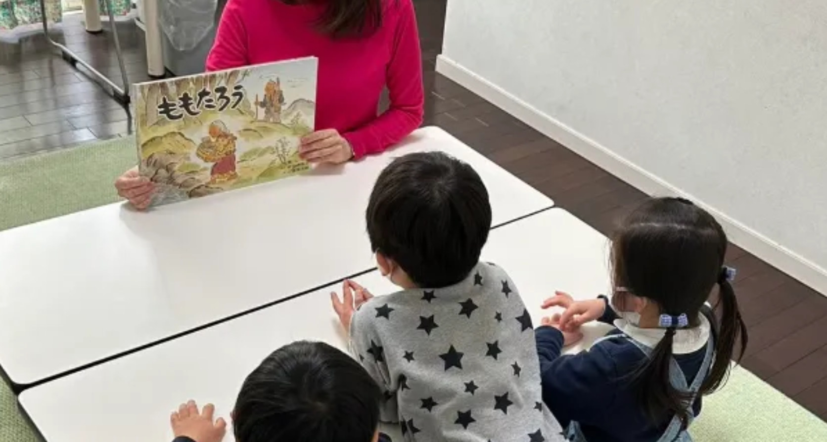 講師が絵本『ももたろう』を子どもたちに読み聞かせている様子